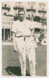 Maurice William Tate. Sussex & England 1912-1937. Sepia real photograph postcard of Tate standing full length wearing cricket attire on the outfield at Hastings. Signed in black ink to the photograph by Tate. Publisher unknown. Postally unused. Very good 