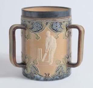 Doulton Lambeth stoneware tyg. Large, than normal, and impressive three handled tyg with three moulded relief vignettes of cricketers, a batsman, a fielder and wicket keeper in white on a brown background with stylised floral leaf and flower Art Nouveau d