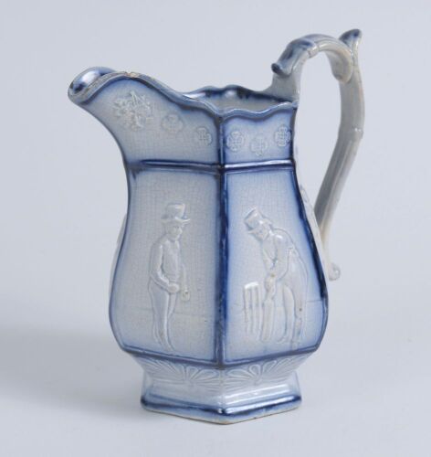 Cricket jug. A light blue mid 19th century Staffordshire salt-glaze jug, the hexagonal bulbous body divided into six panels with cricketers wearing top hats, being Pilch, Clarke and Box. The panels nicely highlighted in a darker cobalt blue. Above and bel
