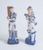 Cricket figures. A pair of German porcelain figures, the boy holding a cricket bat, wearing pads with a cap, the girl in three quarter length dress wearing a cap, she is holding a ball. Each figure is beautifully decorated in blue, red and gold lustre. 9&rdquo;