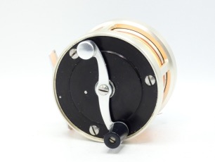 A fine and rare S.E. Bogdan model 150 multiplying salmon fly reel, black/champagne anodised right hand wind model with serpentine crank handle set within an anti-foul rim, block foot, stamped model details, rear milled optional check button and off-set t