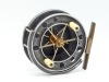 An Allcock Aerial 7950-T6 3 &frac12;" centre pin reel, caged and six spoked drum with twin xylonite handles, perforated front flange (eight holes) and twin regulator/release forks, B.P. line guide, brass stancheon foot and rear sliding optional check button wit