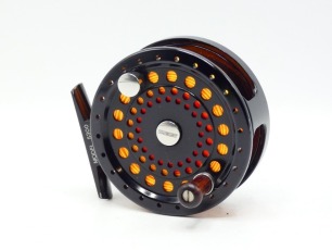 A Sage 5300 trout fly reel and spare spool, left hand wind, black anodised model with counter-balanced rosewood handle, block foot, rear spindle mounted milled tension adjuster, only very light use, in original neoprene cases