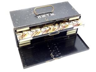 A black japanned rectangular salmon fly reservoir, fall front door opening to reveal seven drawers each with twin ivorine index tabs and brass loop handle , fitted nickel silver spring clips and holding a good selection of 287 fully dressed eyed flies of