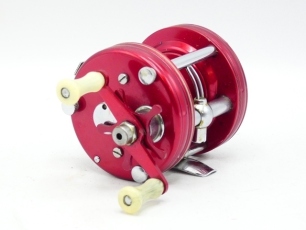 A scarce Record Ambassadeur 5000 bait casting reel, red anodised finish, twin pearlescent handles, grooved rims, six point star drag adjuster, level line mechanism, grey arboured spool, foot stamped 65679", light use only and in original leather case wit