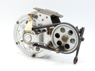 A very rare Kitchen's Patent multiplying salmon casting reel, alloy construction with oyster turned decoration, brass foot, tapered ebonite winding handle on ventilated circular drive plate which rotates an enclosed drum via a spring belt drive whilst al