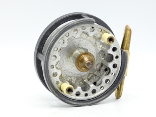 A rare Percy Wadham Carisbrooke 3 &frac14;" centre pin casting reel, skeletal shallow drum with slotted core, twin bulbous ivorine handles and central brass milled locking nut, brass foot, cut-away rim section, rear plate with recessed brass graduated finger bra