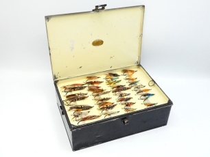 A C. Farlow & Co. rectangular black japanned salmon fly reservoir, cream painted interior with six lift-out trays, each fitted bars of nickel silver spring fly clips, holding a small selection of 34 fully dressed eyed salmon flies, lid interior with appl