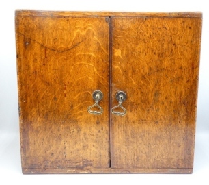 A substantial R. Lewis, St. James's St., London rectangular oak salmon fly cabinet, the twin door cabinet fitted ten sliding drawers, each with turned treen bun handle and brass index slide, paper lined drawer interiors fitted bars of nickel silver sprin