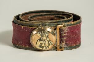 Cricket belt. Early and complete thick leather belt with circular brass belt buckle with figure of an early batsman wearing cap with bat over his shoulder and holding a cricket ball in his other hand. The buckle measures approximately 2&rdquo; diameter. The col