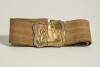 Cricket belt. Early and complete material belt with oblong shaped brass belt buckle showing a bowler bowling to a batsman with trees to background. The buckle measures approximately 2.25&rdquo;x2&rdquo;, the belt in brown material with minor stripes running through i