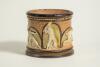Doulton Lambeth stoneware tobacco jar, hand decorated with six moulded relief vignettes of cricketers to each arched roundel, three in various batting poses, one in wicket-keeping pose and two in fielding pose with an impressed overall flower motif on the