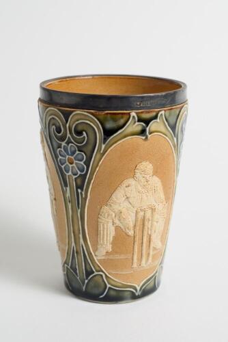 Doulton Lambeth stoneware beaker, moulded with relief vignettes of cricketers, a batsman, bowler and wicket keeper, Abel, Woods and McGregor in white on a brown background. With stylised daisy and floral leaf Art Nouveau decoration to top and sides in gre
