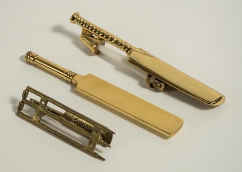 Brass cricket door knockers. Two different door knockers, one, which appears older than the other has a set of brass stumps with bails as the plate and a brass cricket bat knocker with reference/makers number NK1050581 to the underside of the bat, measure