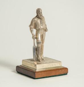 W.G. Grace. Silver figure of W.G. Grace standing wearing cap and in batting pose with bat held to side. The figure mounted to wooden base with title to front &lsquo;W.G. Grace&rsquo;. Hallmarked London 2019 and the silver makers mark NVB for Norman Victor Bassant. Th