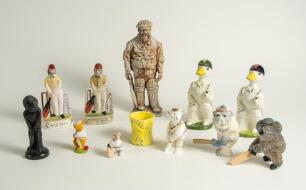 Cricket ceramics and metalware. Varied selection of items including modern metal figures of cricketers, a pair of cricket wicket bookends, a boy cricketer made out of slate, two cricket duck batsman by Acorn Ceramics, a bulldog batsman, a golliwog egg cup