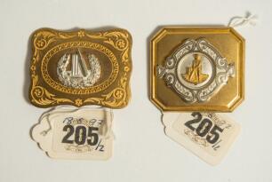 Cricket belt buckles. A pair of belt buckles, both mint tradesman&rsquo;s samples, and unused, in soft gilt metal. the first with silver-plated cricket emblem mounted within engraved floral border on gilt brass backplate, the other with applied gilt metal desig