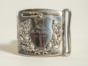 Cricket belt buckle. Silver metal cricket belt buckle of almost square form with laurel wreath garland to centre and cricket bat and ball above. Inscription to centre reads &lsquo;Won by M. Shephard&rsquo;. 14.4. [18]65. Approximately 2.5&rdquo;x2.25&rdquo;. Good condition
