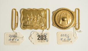 Cricket belt buckles. A pair of belt buckles, both mint tradesman&rsquo;s samples, and unused, in soft gilt metal. One of oblong shape with relief design showing a group of cricketers tossing a ball in the air with legend &lsquo;Toss for the Innings&rsquo; measuring 2.75&rdquo;x