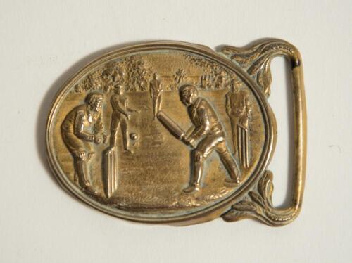 Cricket belt buckle. Brass cricket belt buckle of oval form with scene of a cricket match in progress to centre, batsman, wicket-keeper and fielders to foreground, trees to background. Approximately 2.75&rdquo;x2&rdquo;. Good condition