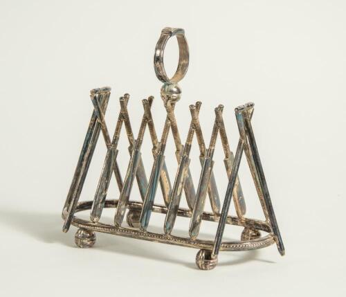 Cricket toast rack c1900. A Victorian silver plated, six division toast rack with five pairs of crossed cricket bats, with a set of angled cricket stumps and bails at each end, the handle of the rack in the form of a cricketer&rsquo;s belt and buckle on a crick