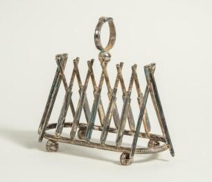 Cricket toast rack c1900. A Victorian silver plated, six division toast rack with five pairs of crossed cricket bats, with a set of angled cricket stumps and bails at each end, the handle of the rack in the form of a cricketer&rsquo;s belt and buckle on a crick