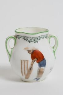 &lsquo;Good for Fifty&rsquo;. Royal Doulton Black Boy miniature two handled vase, with printed image of a boy in red shirt and a floppy hat in batting pose in front of the wicket to one side and to the other, a crest with &lsquo;The All Black Team&rsquo;. Green floral decoration