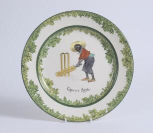 &lsquo;There&rsquo;s Style!&rsquo;. A Royal Doulton Black Boy dinner plate, entitled &lsquo;There&rsquo;s Style!&rsquo; printed with a boy in red jacket and a floppy hat stood in batting stance in front of the wicket. Green floral decoration to inner and outer rim. 9.5&rdquo; diameter. Doulton ba