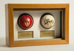 Shane Warne &lsquo;World Record Wicket Taker in Test matches&rsquo; and Wasim Akram &lsquo;World Record Wicket Taker in one day matches&rsquo;. A pair of Duncan Fearnley cricket balls, one red and signed by Warne and one white signed by Akram. Mounted in oak case with printed co