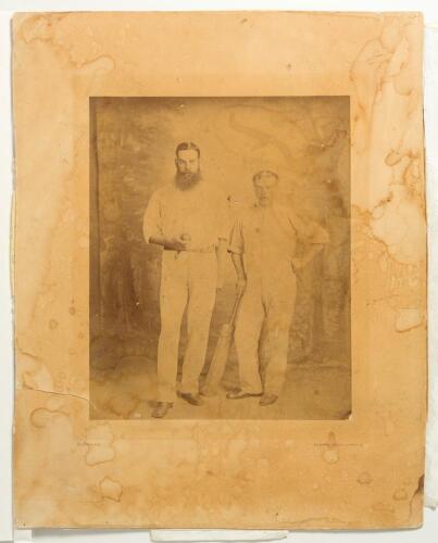 William Gilbert Grace. Gloucestershire & England. 1865-1908 and Henry &lsquo;Harry&rsquo; Jupp, Surrey & England 1862-1881. Original sepia photograph of the two players full length stood side by side, Grace holding a cricket ball and Jupp a cricket bat, both wearing 
