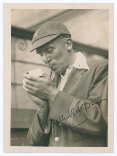 Arthur Edward Robert Gilligan. Cambridge University, Surrey, Sussex & England 1919-1932. Mono photograph of Gilligan, half length, wearing M.C.C. blazer and England cap lighting up his pipe. Signed in ink to the photograph by Gilligan. The photograph meas