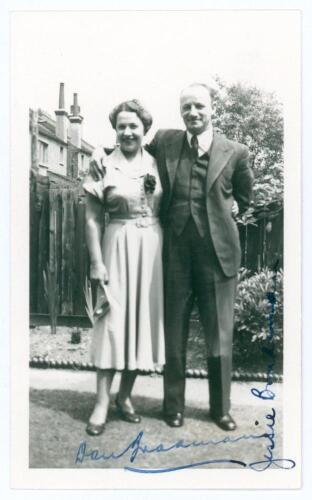 Don Bradman. Small original candid mono photograph of Bradman standing full length in formal attire, his arm around the shoulder of his wife, Jessie. Signed in blue ink to the photograph by both Don and Jessie Bradman. Annotation in ink to verso, &lsquo;July 19